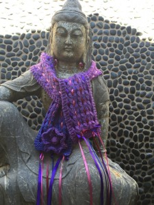 Dappled Sunlight Scarf adorned with ribbons and knitted flower.